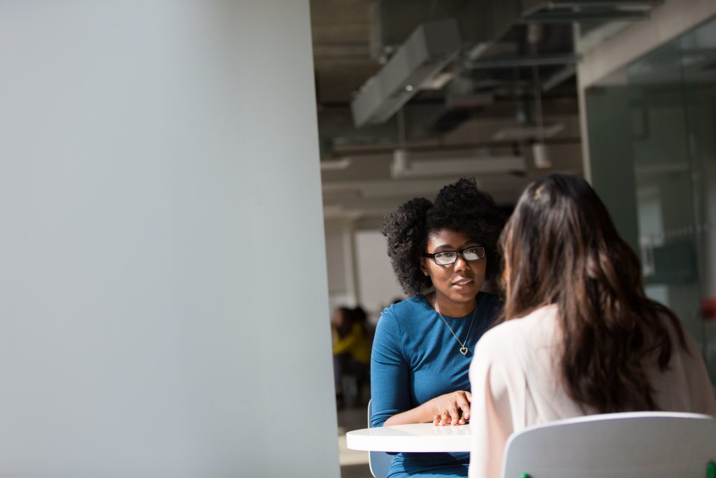 Two individuals sitting, facing each other in a supportive conversation.